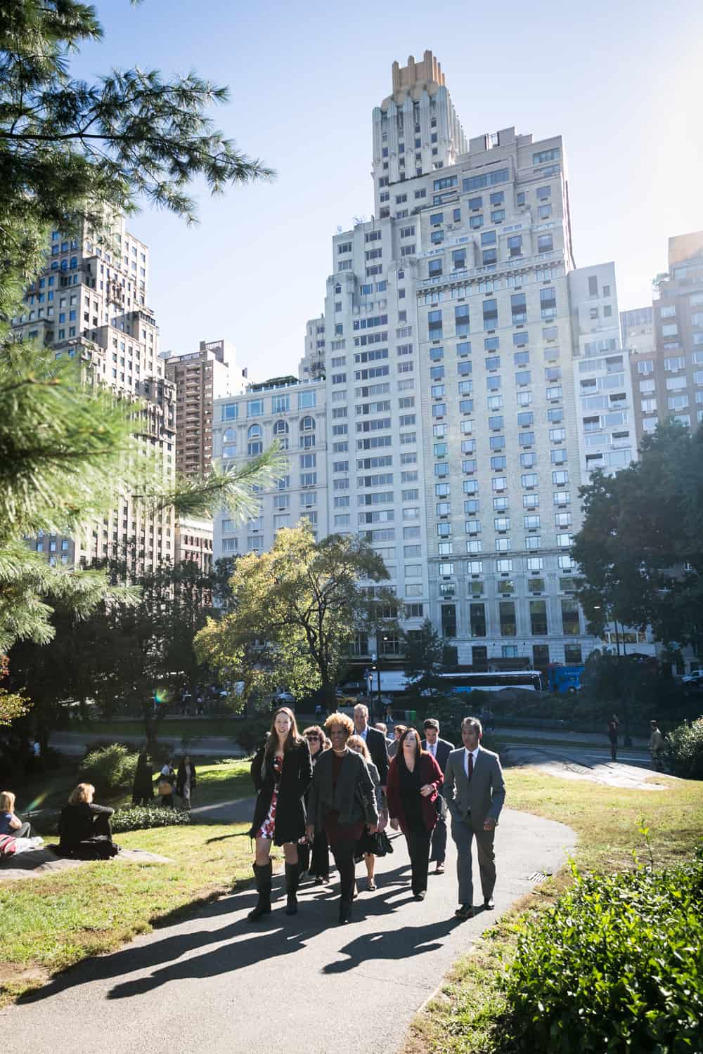 Guests walking up pathway with NYC skyline in background for an article on Central Park wedding planning tips