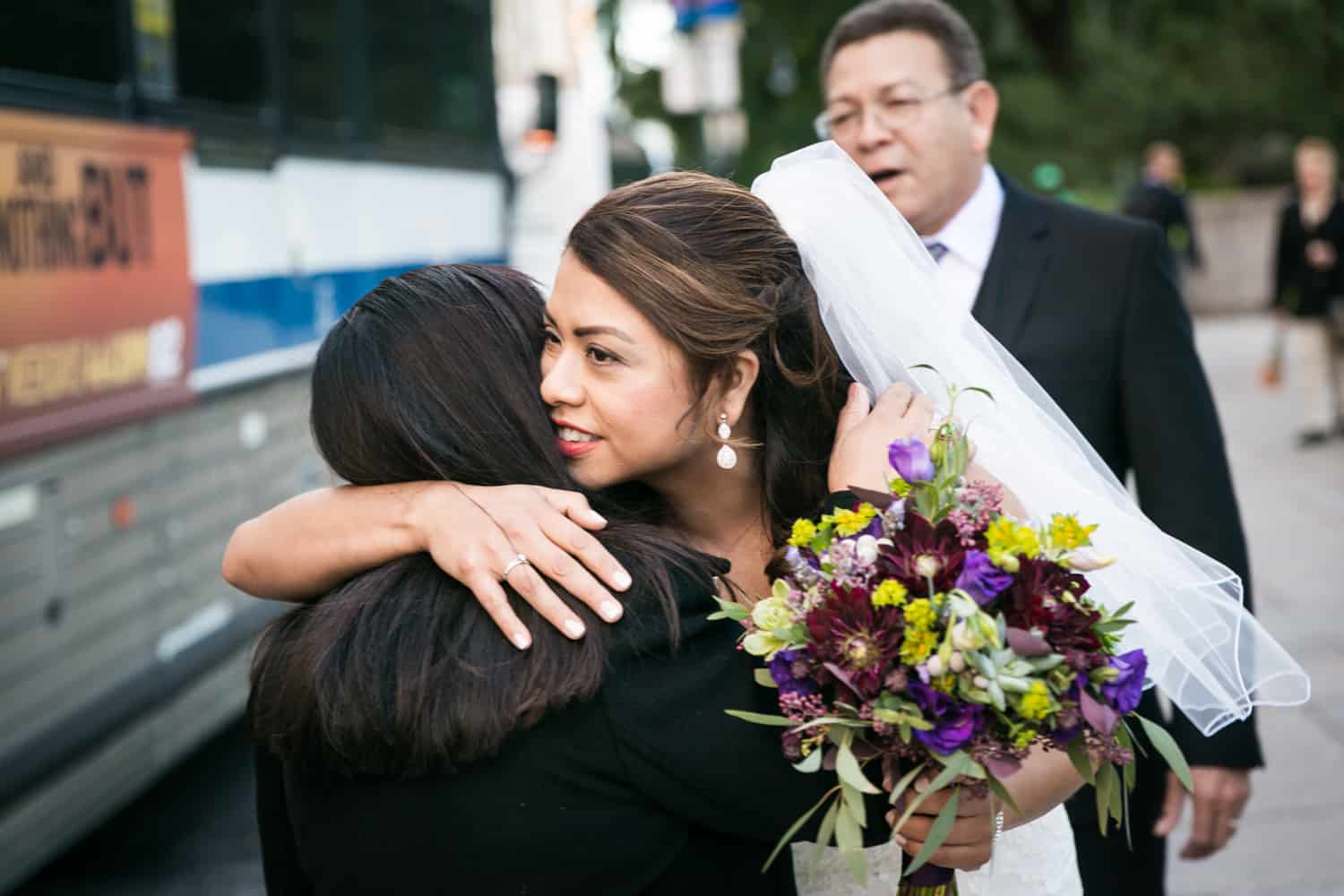 Bride holding bouquet and hugging mother for an article on Central Park wedding planning tips