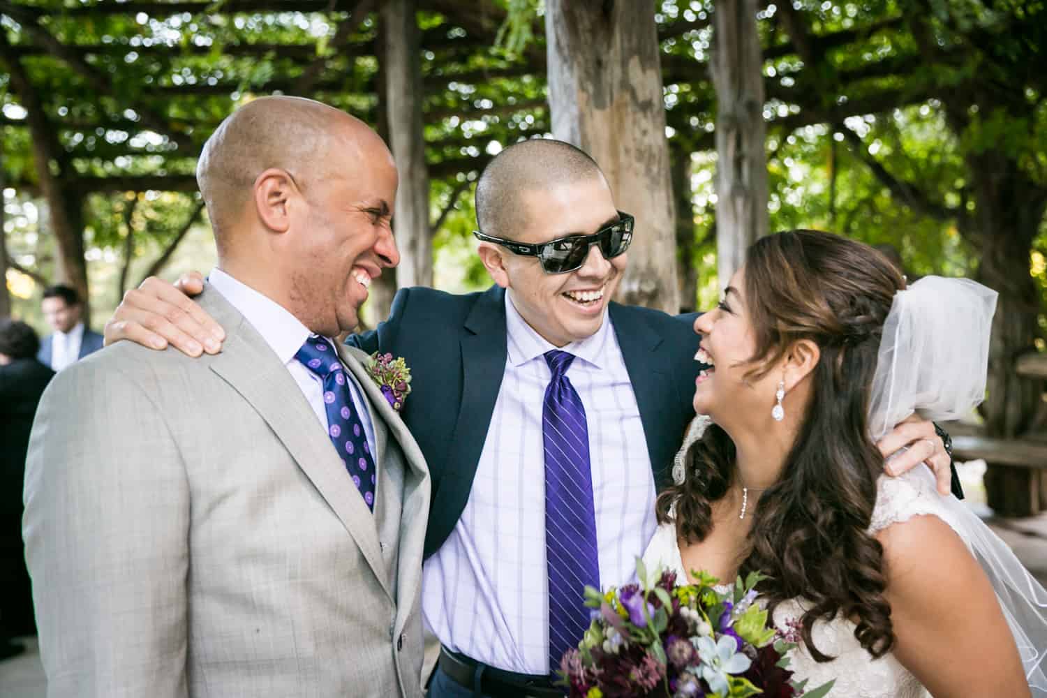 Bride and groom with male guest wearing sunglasses