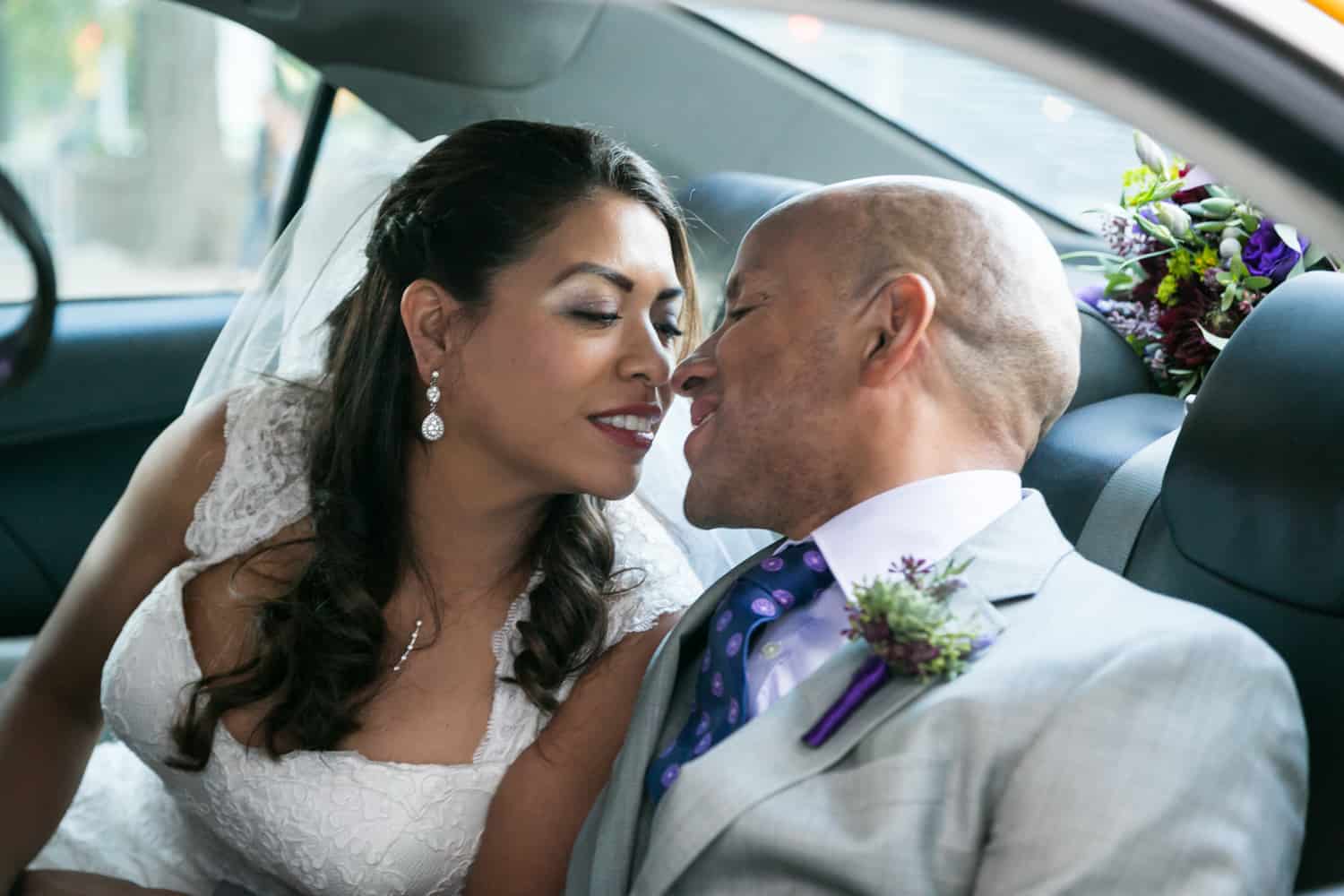 Bride and groom about to kiss in the back of a taxi cab