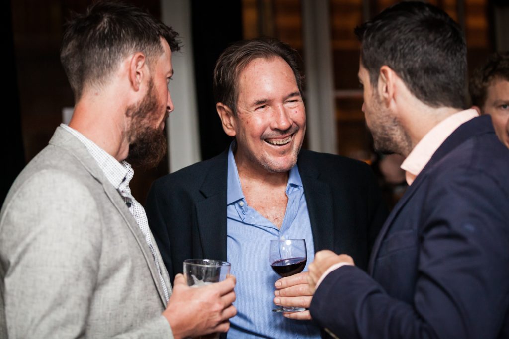 Male guest talking with other guests at rehearsal dinner for an article on how to book hotel room blocks