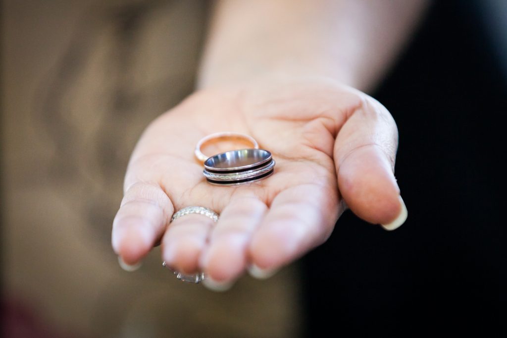 Close up of officiant's hand holding out wedding rings
