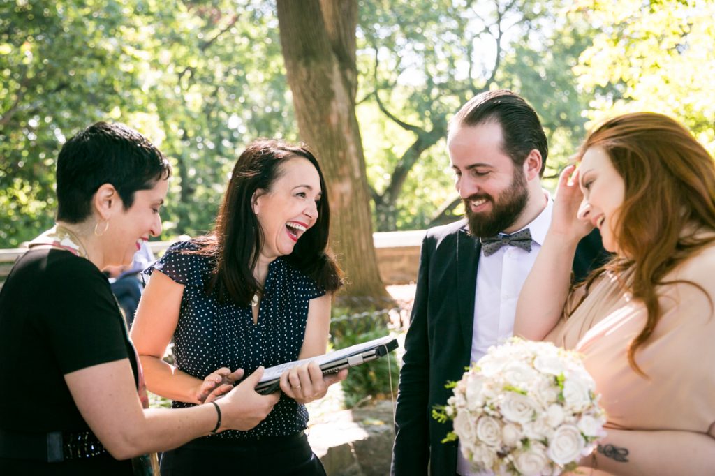 Bride, groom, officiant, and wedding planning laughing together for an article on how to plan a destination wedding