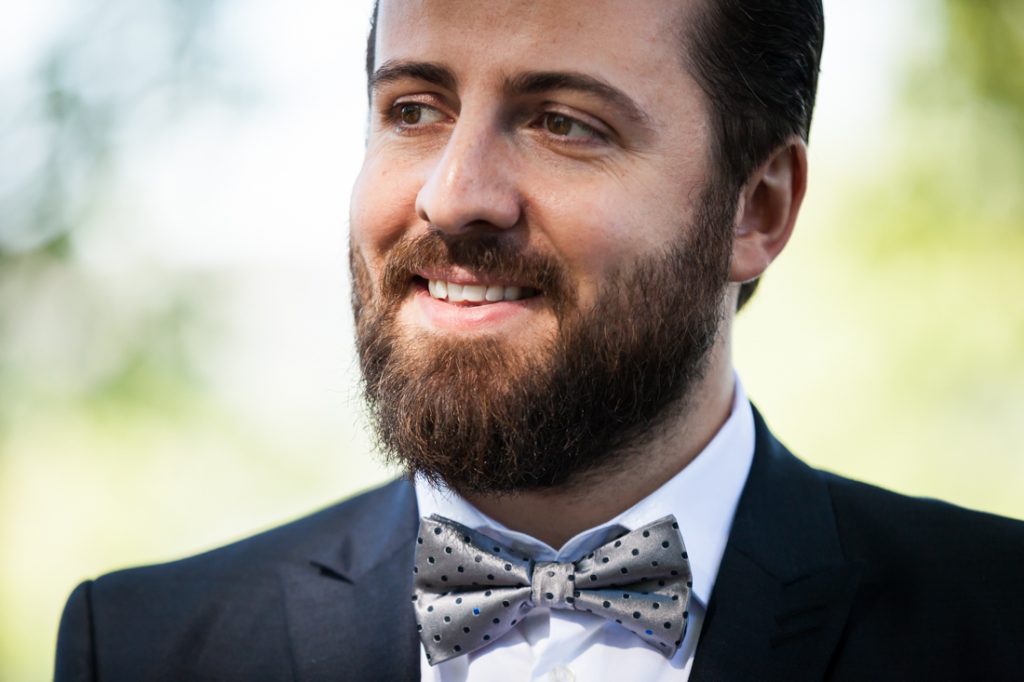 Groom wearing grey bow tie and looking to side