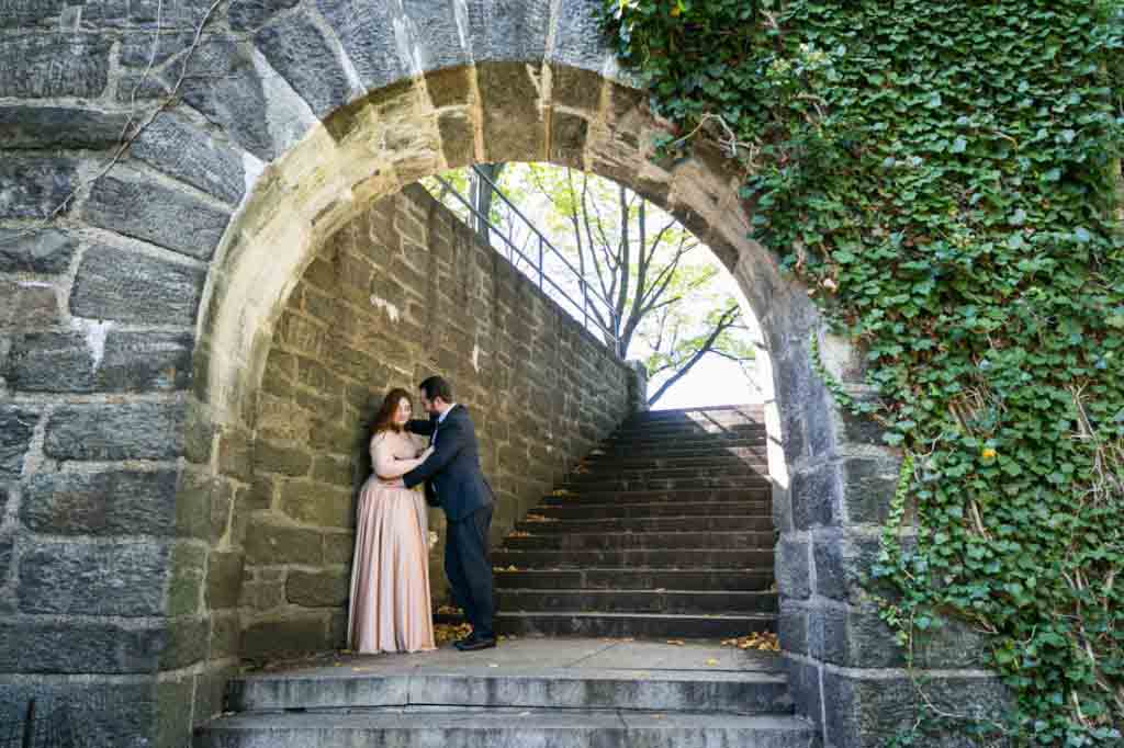 Bride and groom against stone wall in Fort Tryon Park