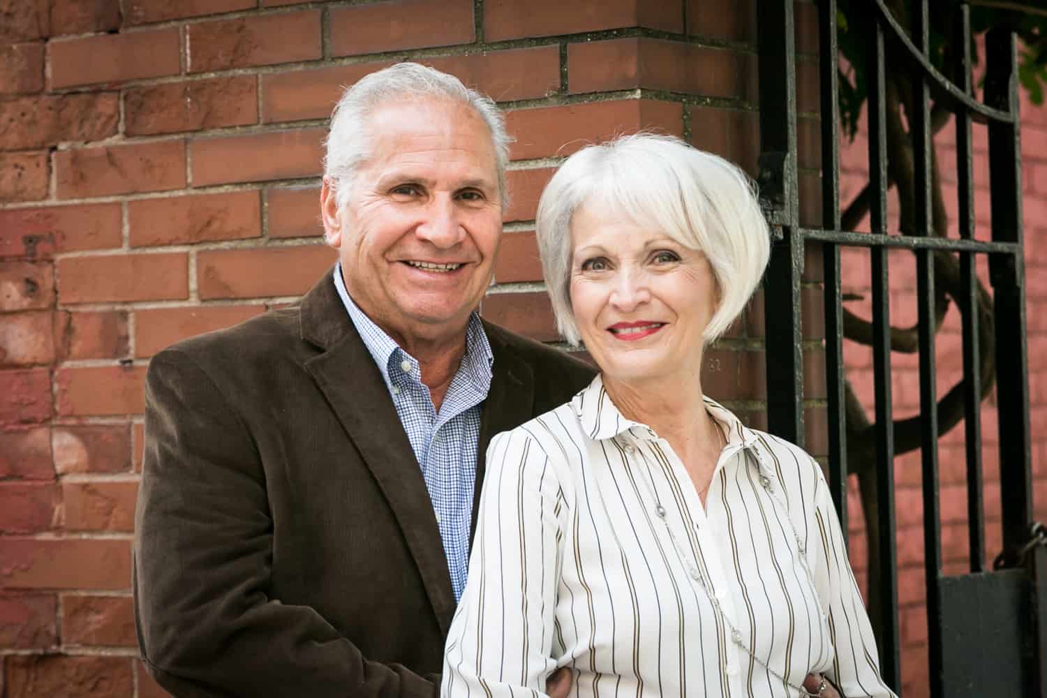 Photojournalistic portraits of older couple with brick wall background