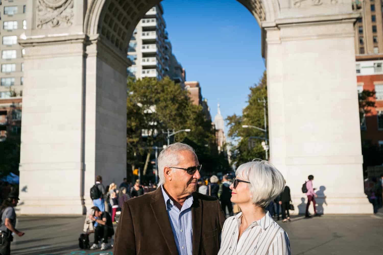 Photojournalistic portraits of older couple wearing sunglasses in front of Washington Square Park arch