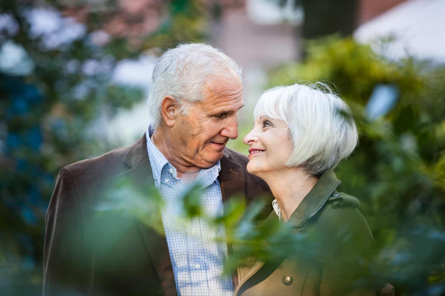 View through branches of older couple looking at one another