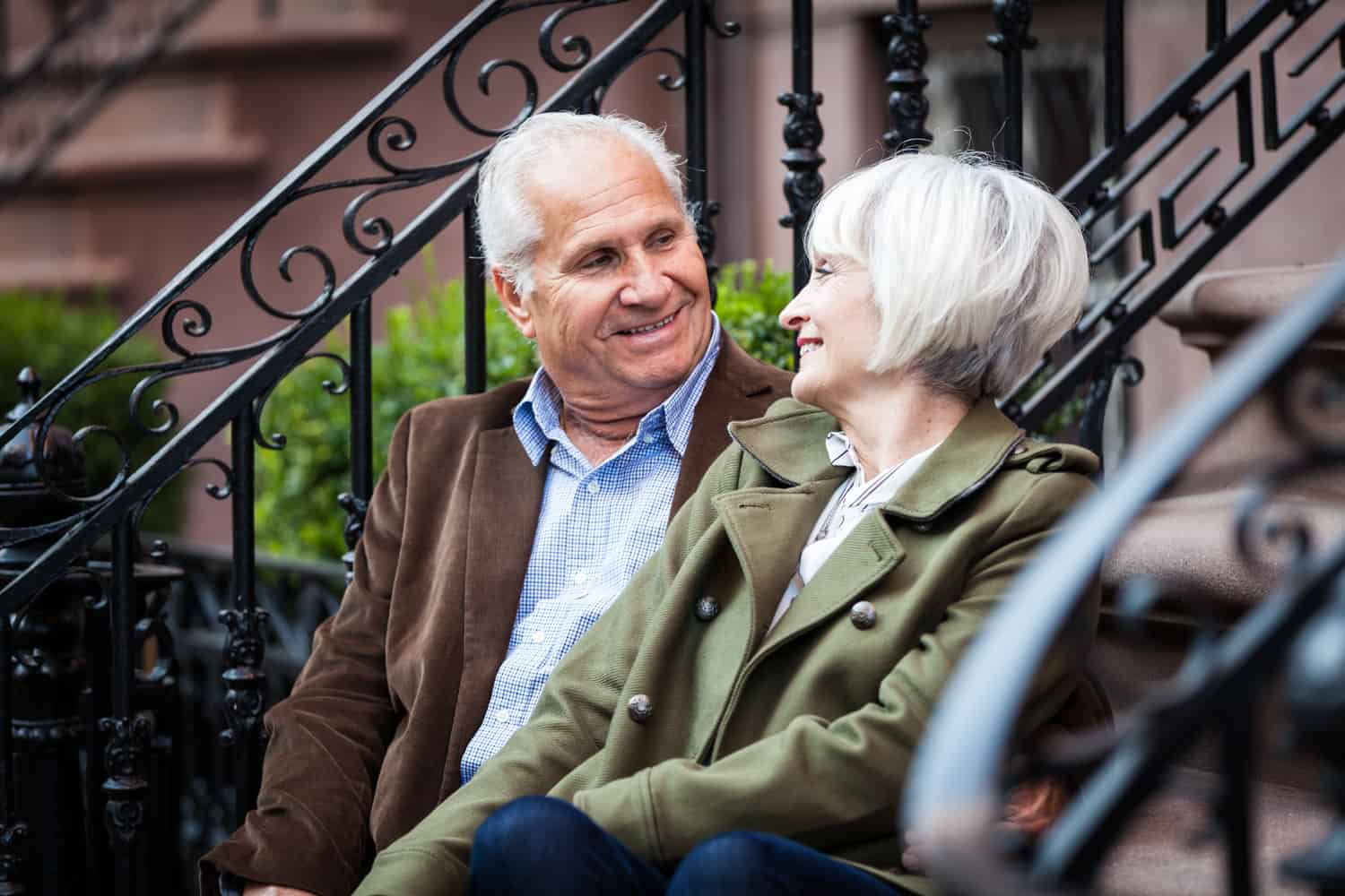 Older couple looking at one another while sitting on brownstone stairs