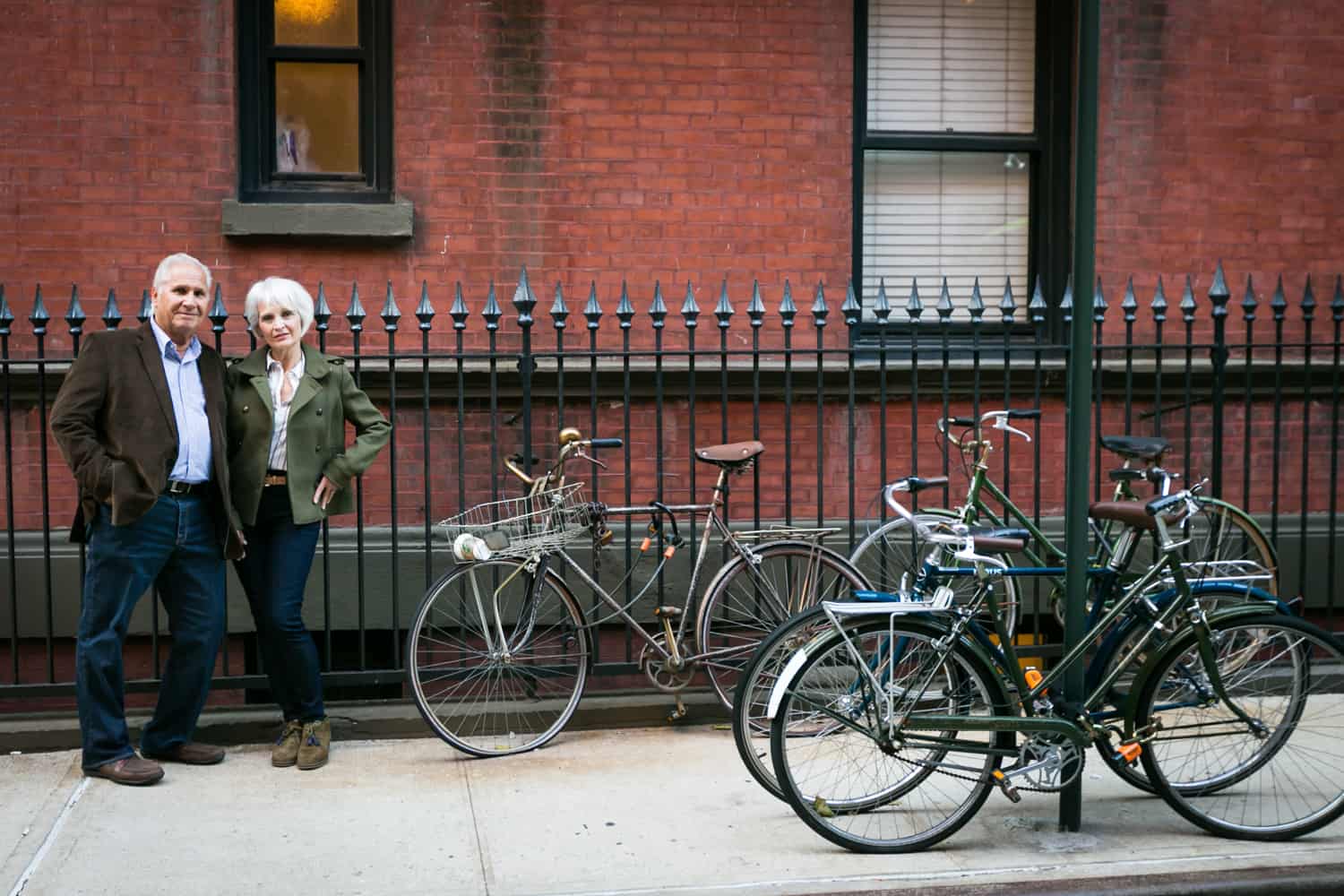 Older couple leaning on fence to left of parked bicycles