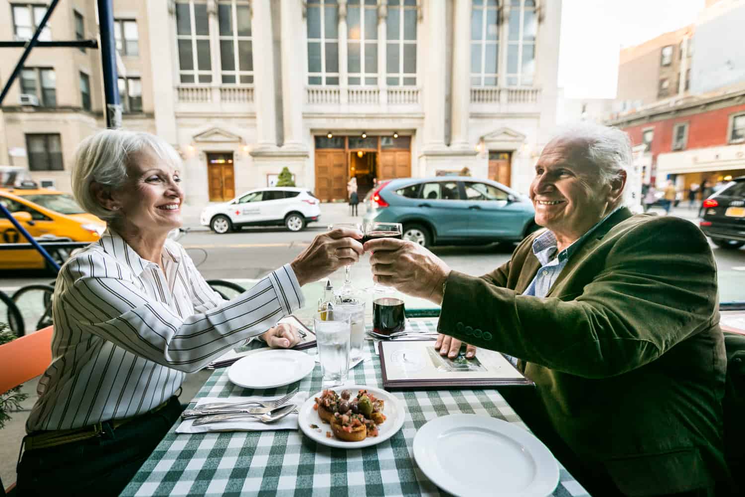 Older couple toasting glasses at sidewalk restaurant