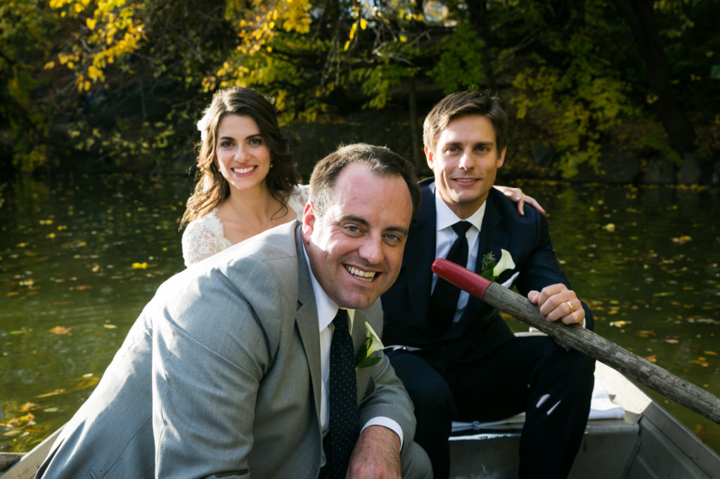 Bride, groom, and groomsman in a Central Park rowboat