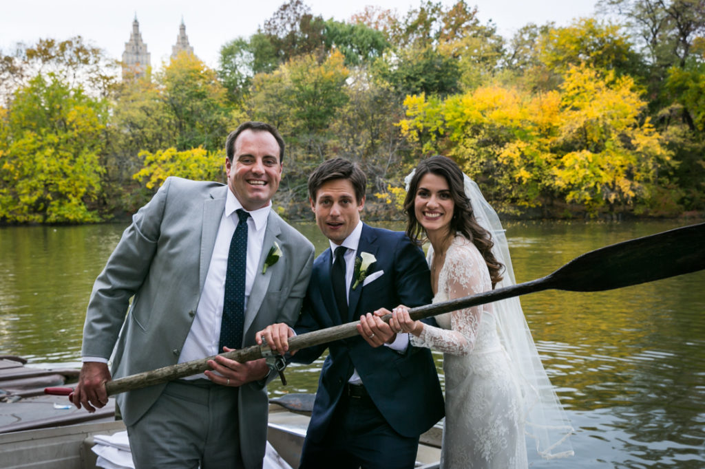 Bride, groom, and groomsman in a Central Park rowboat