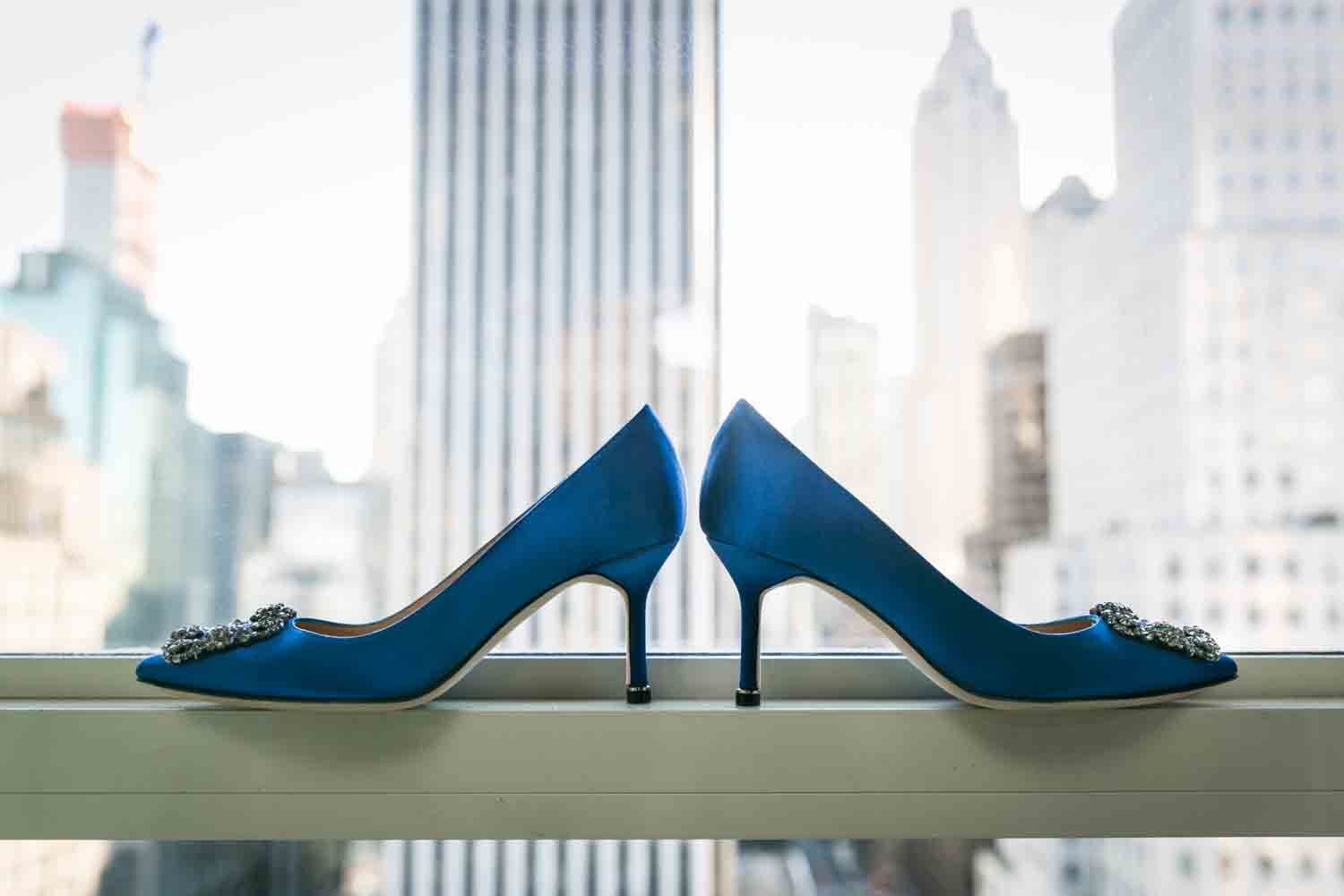 Blue Manolo Blahnik heels in windowsill with NYC skyline in background