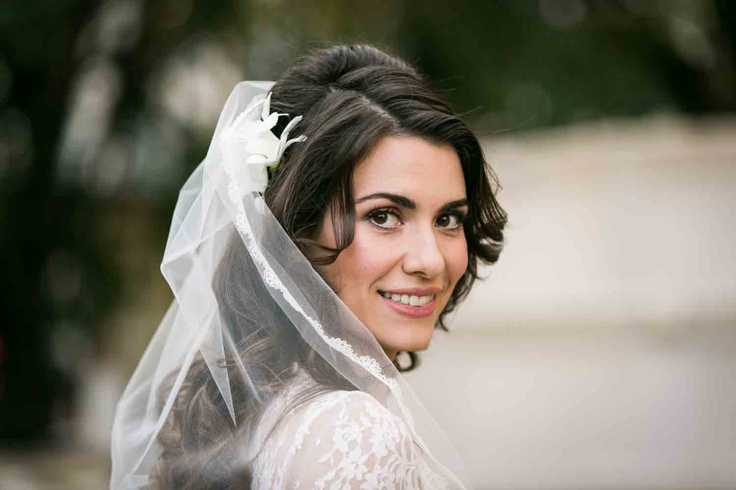 Portrait of bride wearing veil looking over shoulder
