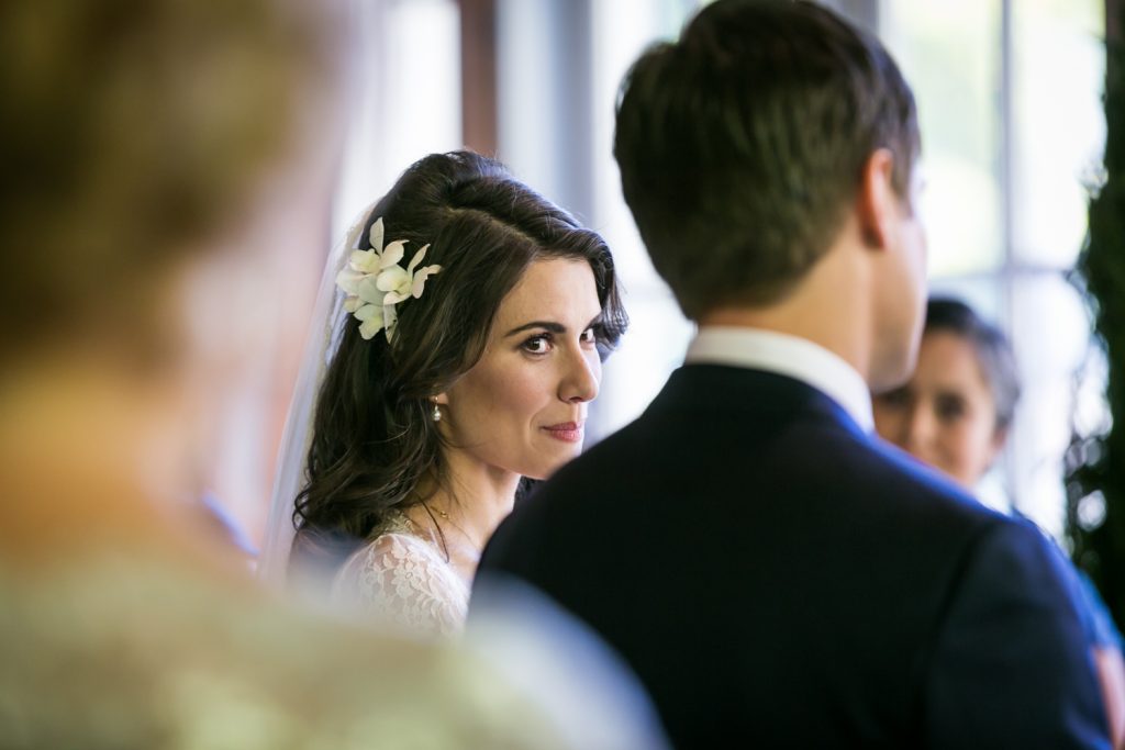 Bride looking over at groom during ceremony at a Loeb Boathouse wedding in Central Park