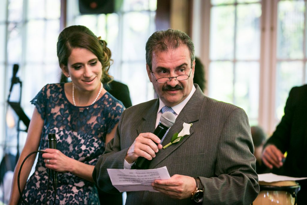 Father of the bride making a speech and maid of honor looking at his paper