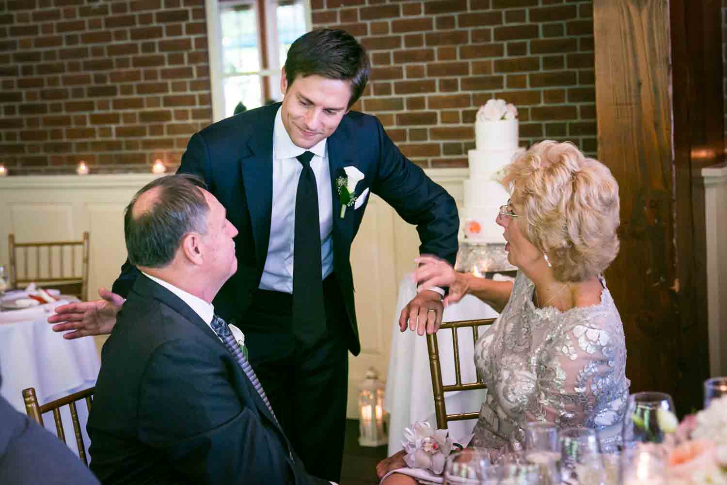 Groom talking with parents seated at table