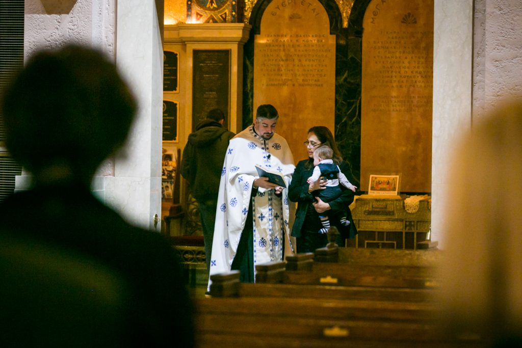 Priest administering rights in cathedral doorway by NYC Greek orthodox baptism photographer, Kelly Williams