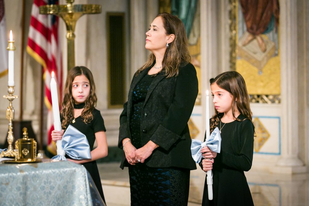 Little girls holding candles beside godmother by NYC Greek orthodox baptism photographer, Kelly Williams