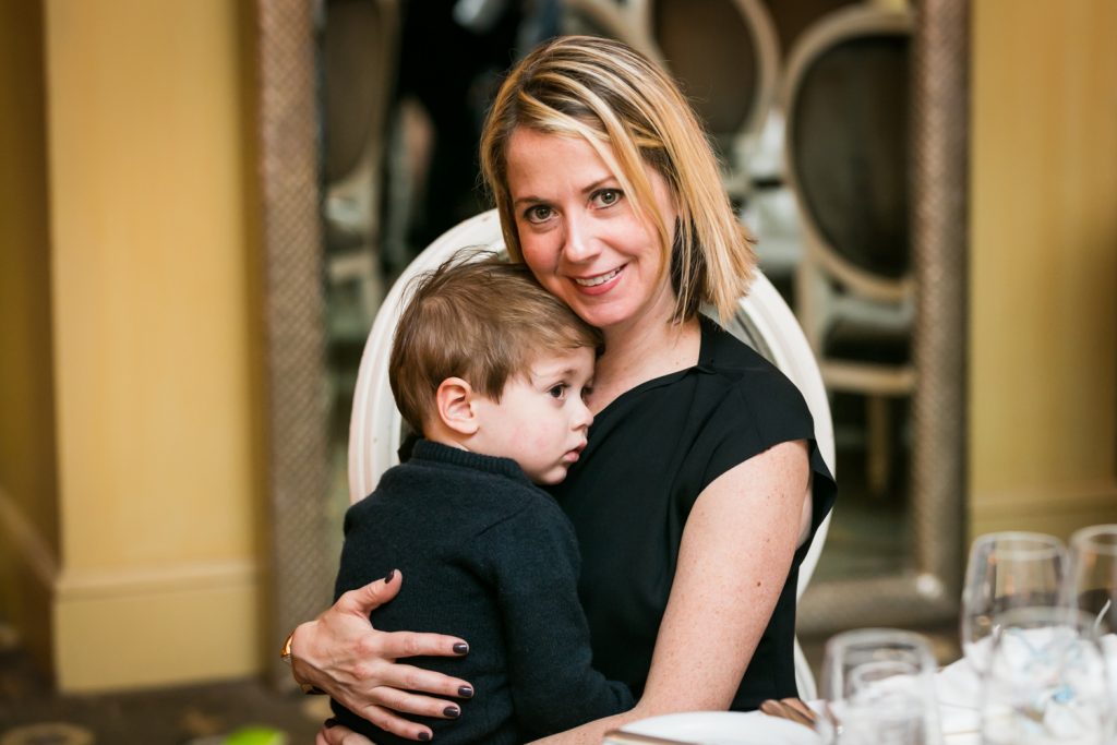 Guest holding little boy in lap by NYC Greek orthodox baptism photographer, Kelly Williams