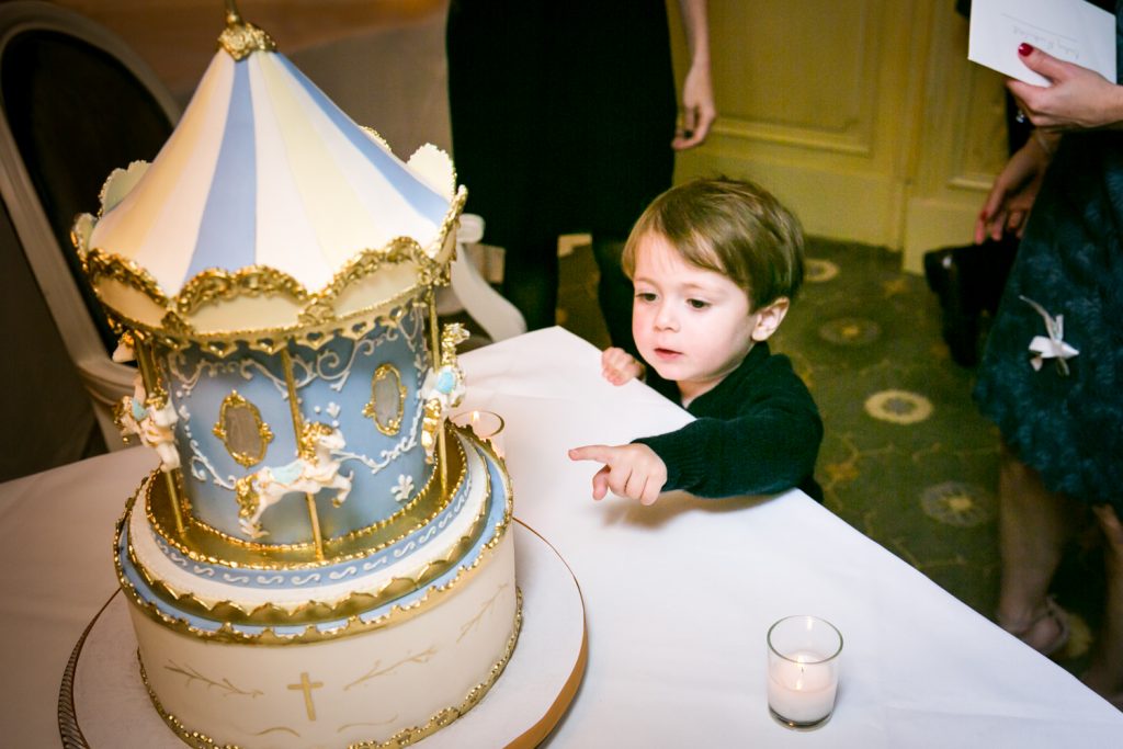 Little boy about to touch cake by NYC Greek orthodox baptism photographer, Kelly Williams