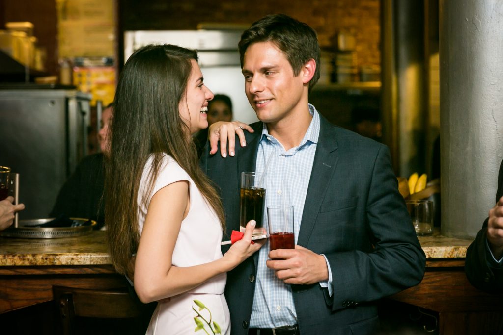 Couple talking and holding drinks during rehearsal dinner