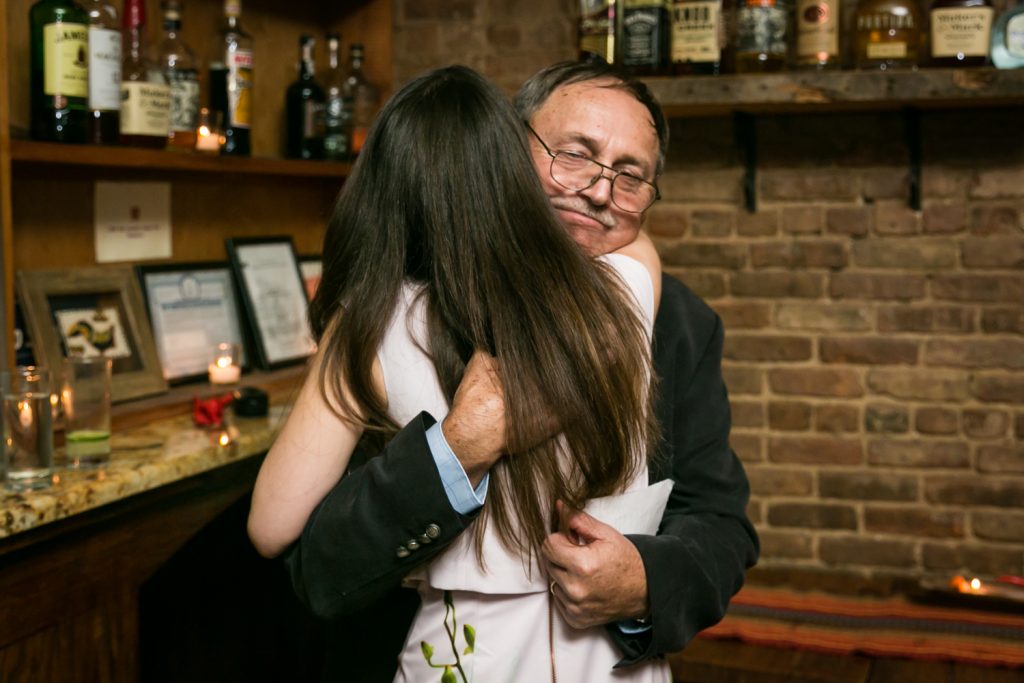 Father of the groom hugging bride during rehearsal dinner
