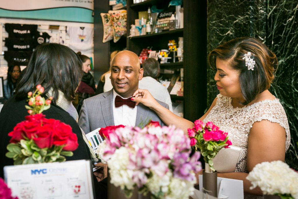 Bride adjusting groom's tie in flower shop for an article on wedding website tips