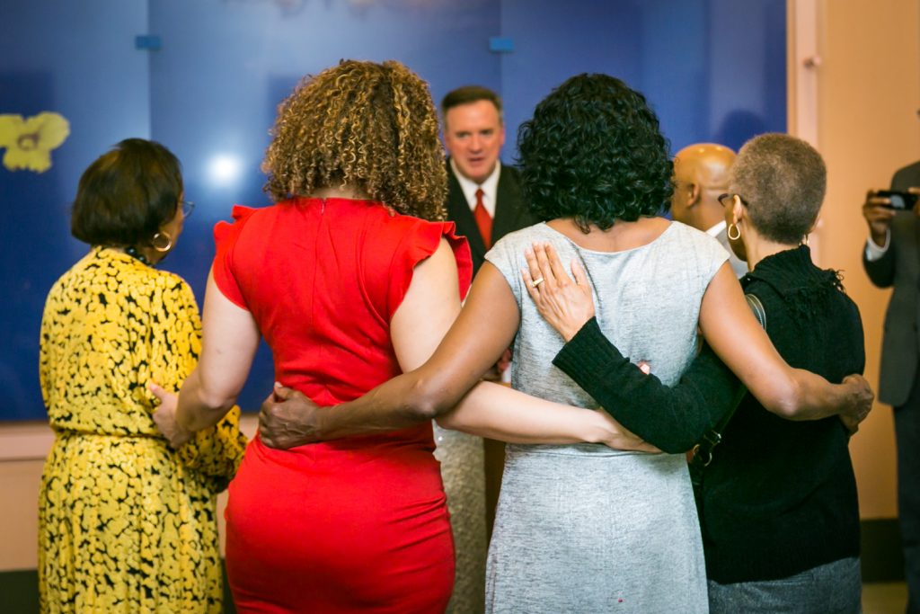 Photo of guests from the back with arms around each other for an article on wedding website tips