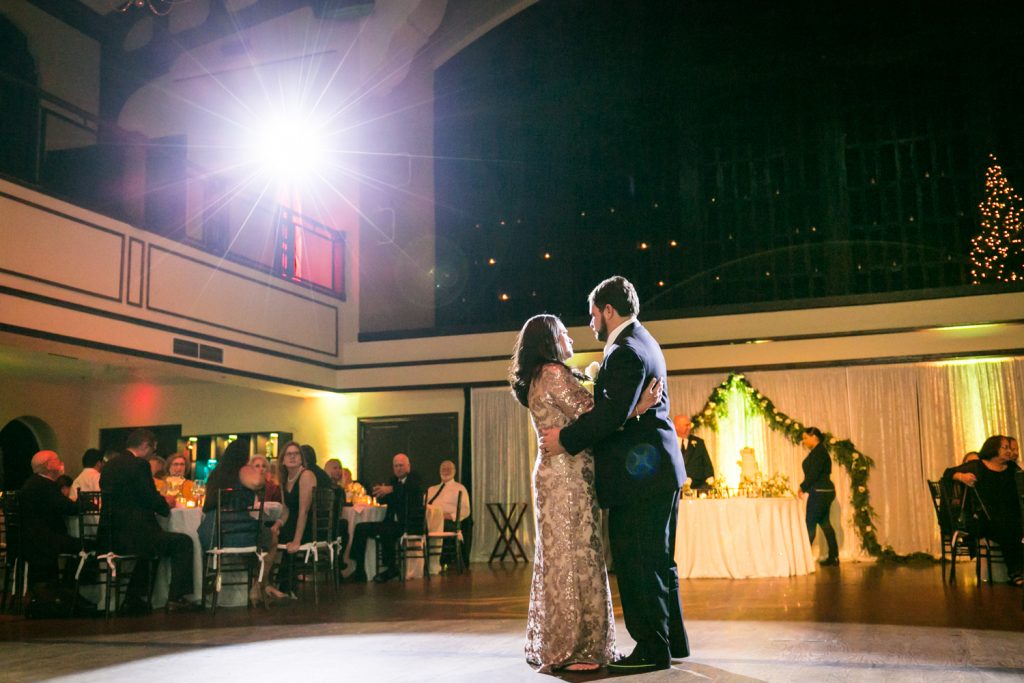 Groom and mother dancing with spotlight overhead for an article on how DJ lighting affects your wedding photos