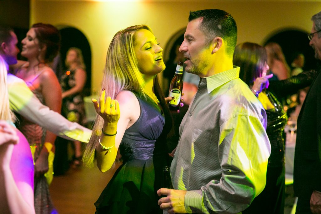 Couple bathed in yellow light dancing at a reception for an article on how DJ lighting affects your wedding photos