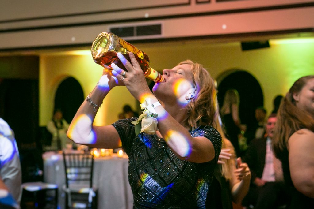 Mother of the bride drinking for bottle of Fireball for an article on how DJ lighting affects your wedding photos