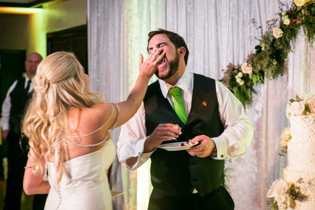 Groom shoving cake in groom's face at a West Palm Beach wedding