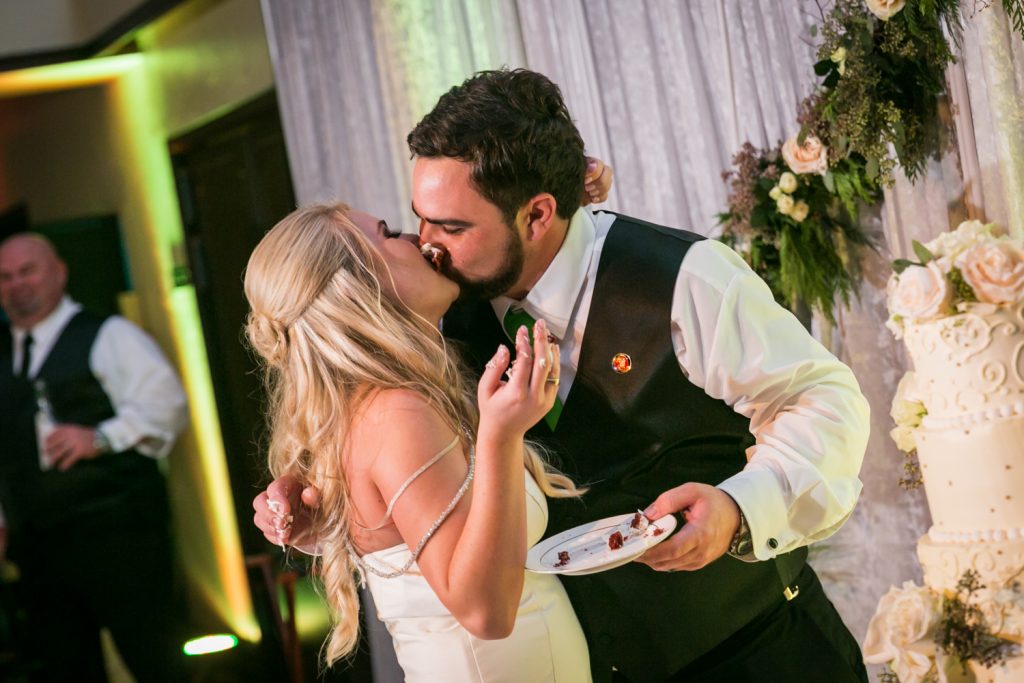 Bride and groom kissing after cutting cake at a West Palm Beach wedding
