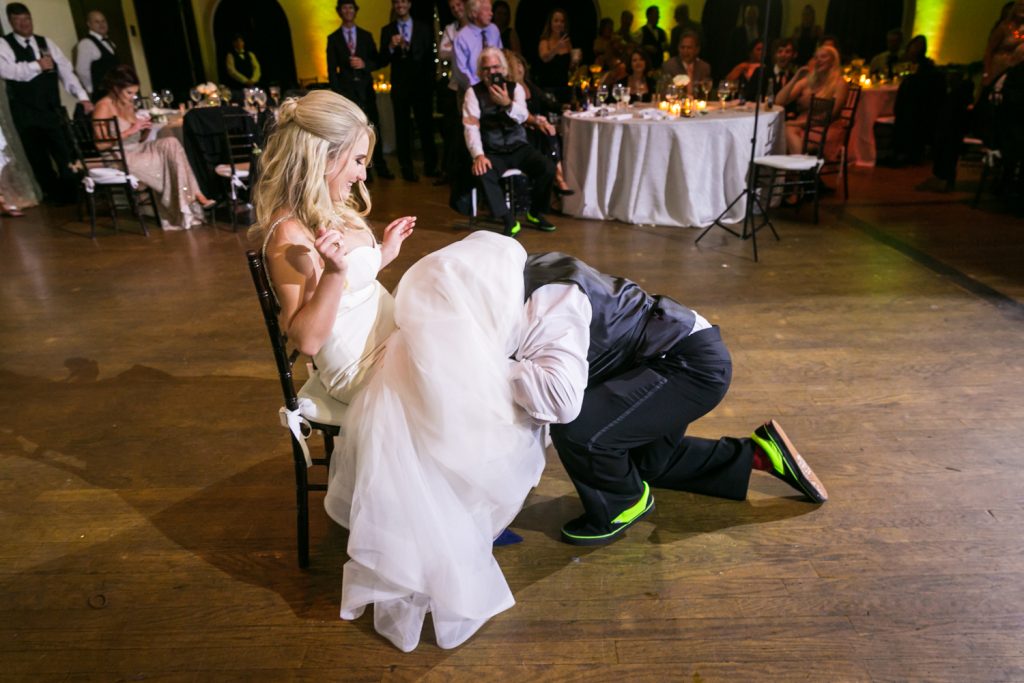 Groom under bride's dress to find garter at a West Palm Beach wedding