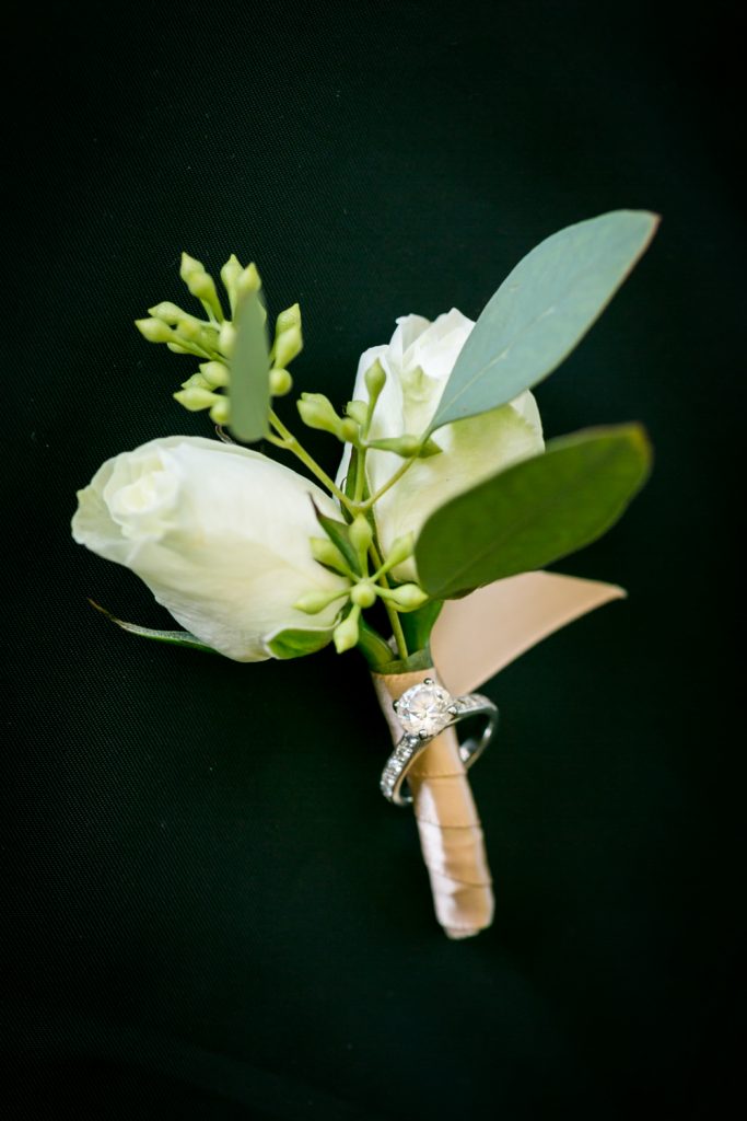 White rose boutonniere with engagement ring for an article on how to have an unplugged wedding