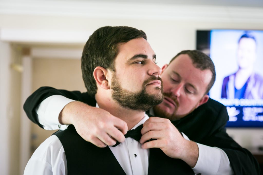Groomsmen adjusting groom's bow tie for an article on how to have an unplugged wedding