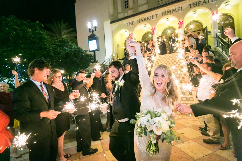 Bride and groom walking down staircase at Harriet Himmel Theater surrounded by guests with sparklers