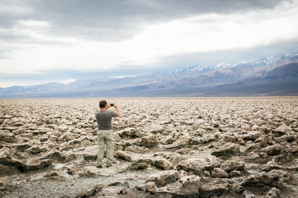 Male tourist taking photos of rock formations in the Devil's Golf Course in Death Valley National Park