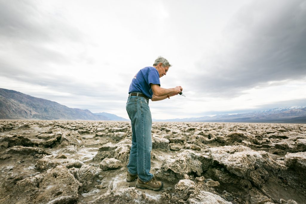 Male tourist taking photos of rock formations in the Devil's Golf Course in Death Valley National Park