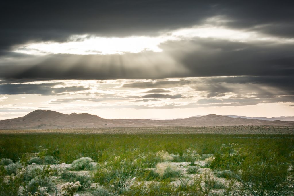 Light shining through clouds with mountains in Mojave National Preserve
