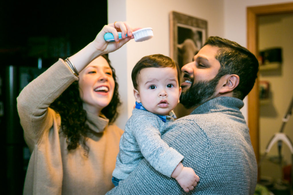 Parents brushing their child's hair for an article on indoor baby portrait tips