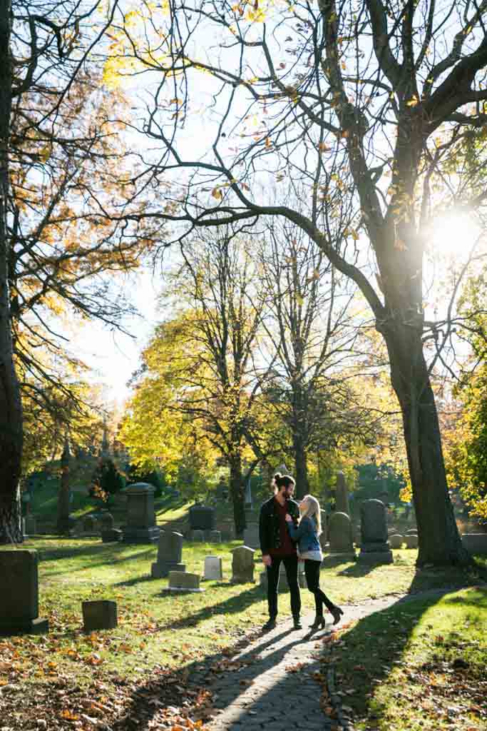 Green-Wood Cemetery engagement photos of couple walking between trees