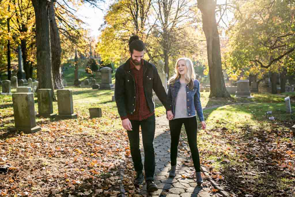 Green-Wood Cemetery engagement photos of couple holding hands and walking along path