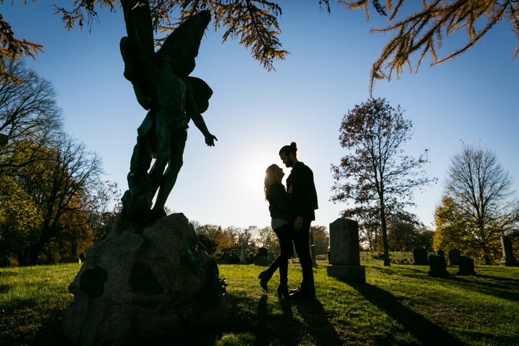 Green-Wood Cemetery engagement photos of backlit couple by angel statue