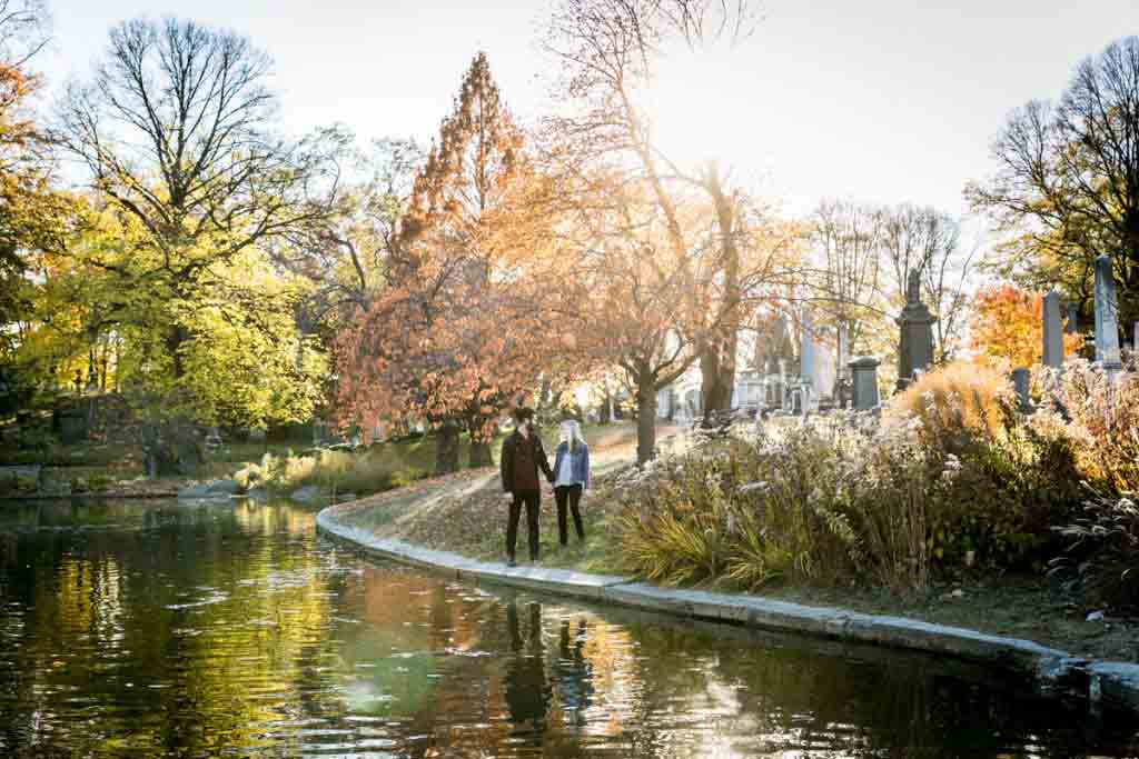 Green-Wood Cemetery engagement photos of couple walking along pond