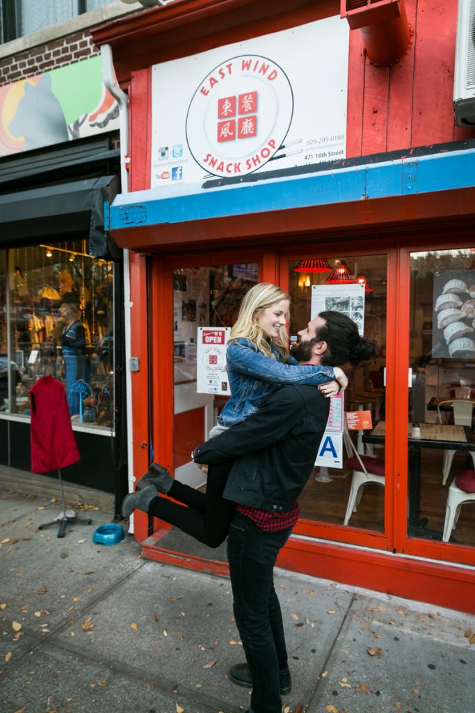 Windsor Terrace engagement photos of man lifting up woman in front of Chinese restaurant