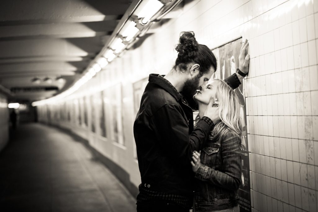 Black and white photo of couple kissing in subway station