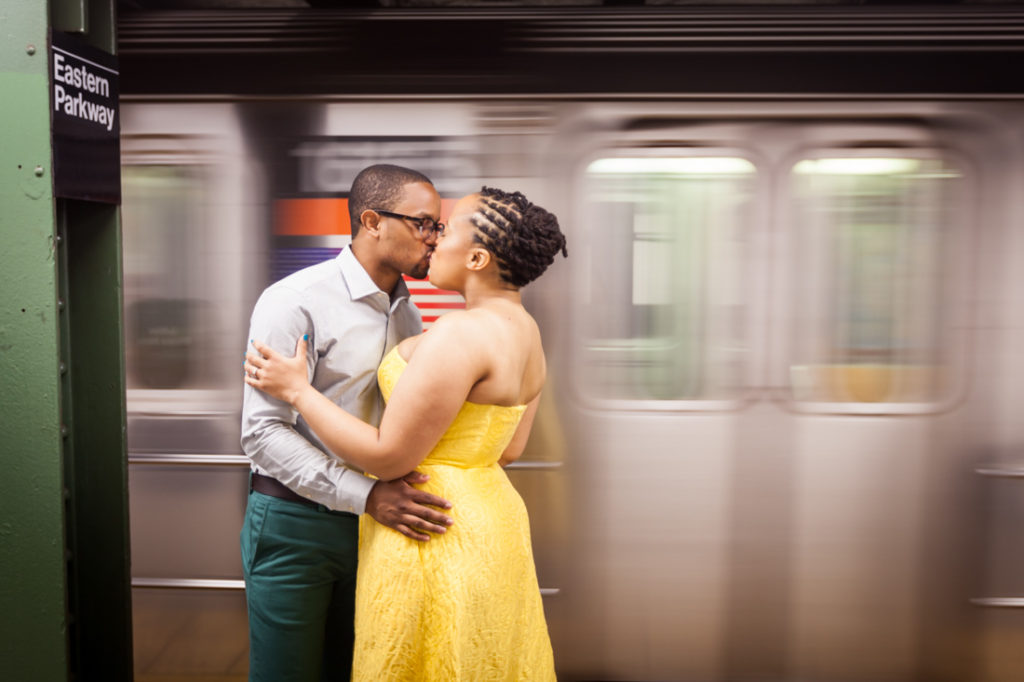 Couple kissing with speeding subway train for an article on best engagement photos